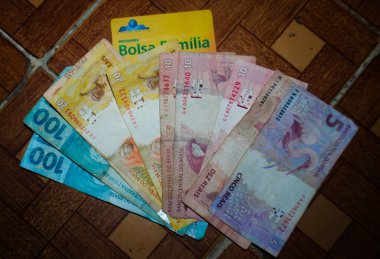 Gerçek banknotların ve Bolsa Aile Sosyal Programı kartının resimli görüntüsü. 22 Kasım 2021, Sao Paulo, Brezilya. Hükümet tarafından oluşturulan Bolsa Aile Sosyal Programı 'ndan gerçek banknotların ve kartların tasviri. 