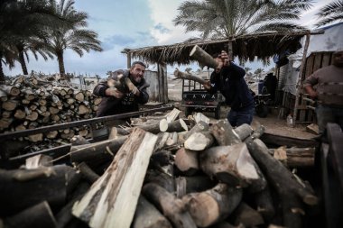 Filistinli işçiler Gazze 'de kışın odun satmak için odun kestiler. 3 Aralık 2021, Gazze, Filistin: Filistinli işçiler, Filistin 'deki Gazze Şeridi' nde talep çok yüksek olduğu Cuma günü, kış mevsiminde müşterilere odun satmak için odun kesiyorlar.)