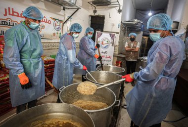 Filistinliler Gazze 'deki kutsal Ramazan ayında yemek pişirip fakirlere dağıtıyorlar. 4 Nisan 2022, Gazze, Filistin: Filistinli gönüllüler, kutsal Ramazan ayında ücretsiz yemek pişiriyor ve yoksul ailelere dağıtıyorlar.