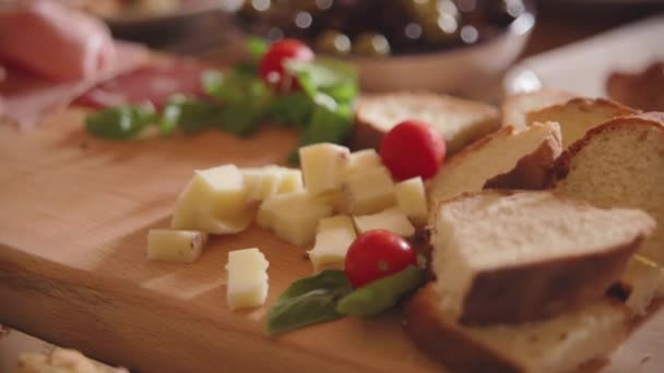 Кілька скибочок сиру з вишневим помідором, базиліком і брушетта на дерев'яній обробній дошці — стокове відео