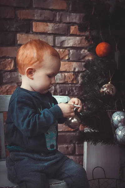 Geyik desenli süveter giymiş kızıl saçlı bir çocuk Noel ağacını süslüyor. Bir mucize bekliyor, Noel için hazırlanıyor. Çocukların hayalleri, çocukluk