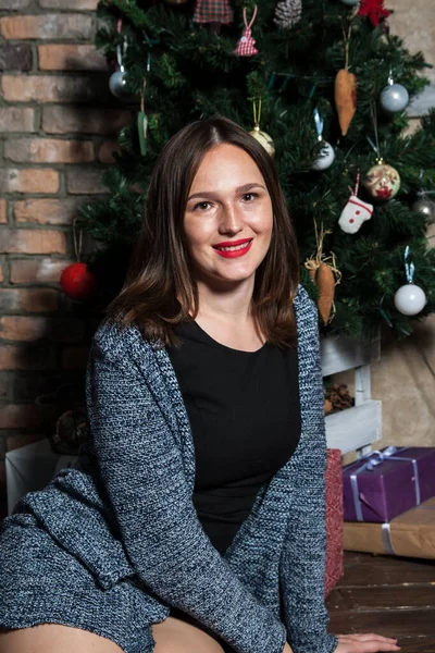 Parlak makyajlı ve kırmızı dudaklı kız Noel ağacının yanında