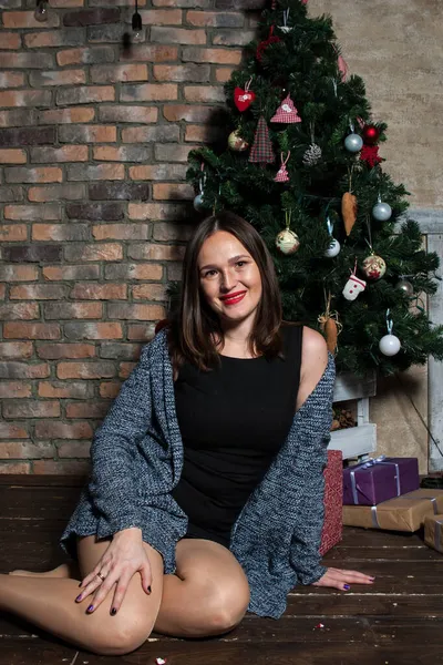 Makyajlı ve kırmızı dudaklı güzel kız Noel ağacının yanında.