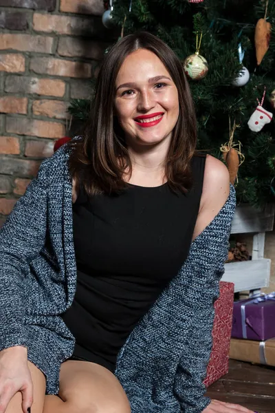 Makyajlı ve kırmızı dudaklı güzel kız Noel ağacının yanında.