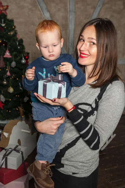 Mutlu anne ve tapılası bebeğin portresi Noel 'i kutluyor. Yeni yıl tatili. Annenle birlikte Noel ağacı ve süslemelerle süslenmiş bir odada..