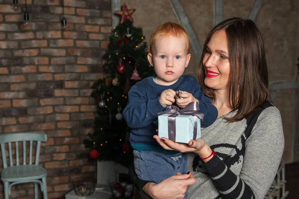 Mutlu anne ve tapılası bebeğin portresi Noel 'i kutluyor. Yeni yıl tatili. Annenle birlikte Noel ağacı ve süslemelerle süslenmiş bir odada..