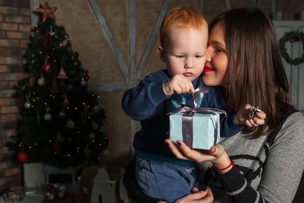 Mutlu anne ve tapılası bebeğin portresi Noel 'i kutluyor. Yeni yıl tatili. Annenle birlikte Noel ağacı ve süslemelerle süslenmiş bir odada..