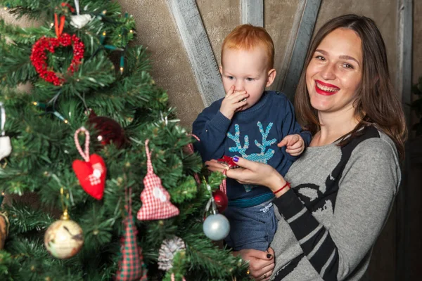 Mutlu anne ve tapılası bebeğin portresi Noel 'i kutluyor. Yeni yıl tatili. Annenle birlikte Noel ağacı ve süslemelerle süslenmiş bir odada..