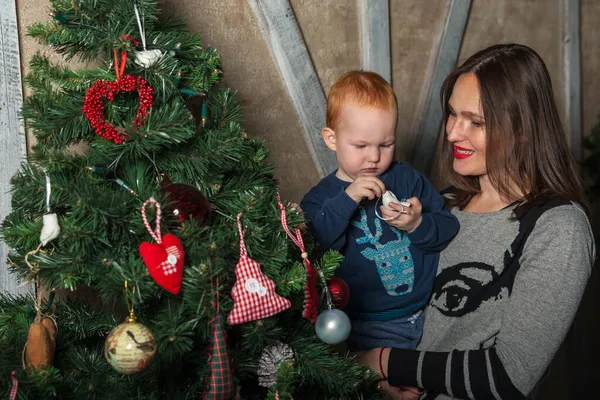 Mutlu anne ve tapılası bebeğin portresi Noel 'i kutluyor. Yeni yıl tatili. Annenle birlikte Noel ağacı ve süslemelerle süslenmiş bir odada..