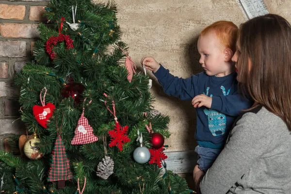 Mutlu anne ve tapılası bebeğin portresi Noel 'i kutluyor. Yeni yıl tatili. Annenle birlikte Noel ağacı ve süslemelerle süslenmiş bir odada..