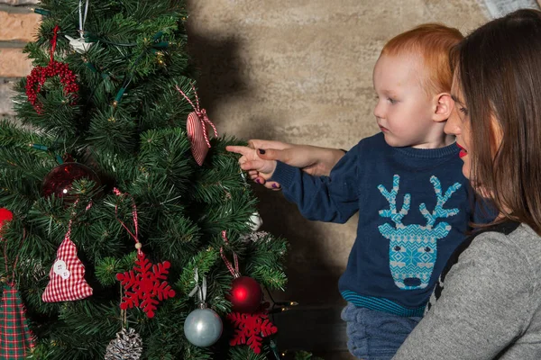Mutlu anne ve tapılası bebeğin portresi Noel 'i kutluyor. Yeni yıl tatili. Annenle birlikte Noel ağacı ve süslemelerle süslenmiş bir odada..