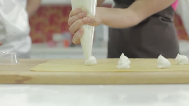 Close-up de um chef de pastelaria espremendo creme de um saco de pastelaria em um bolo — Vídeo de Stock