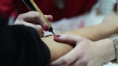 Usta Mehndi kozmetik prosedürlerini gerçekleştiriyor. Kadınlar müşterilerinin ellerini geçici kına dövmeleriyle süslüyor.