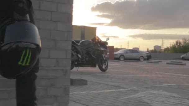 Мотоциклист едет к мотоциклу, держа в руке шлем.. — стоковое видео