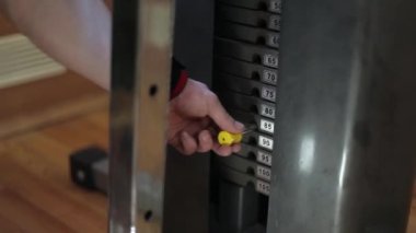Adamın yakın çekim yükünü artırmak için spor salonunda ağırlık plakası ağırlık makinesi değiştirir.