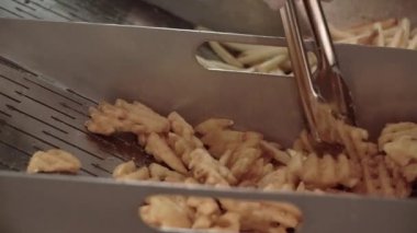 Fast Food, Patates kızartması. Bir insan maşayla patates kızartması yer.