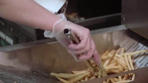 Fast Food, Cozinhar batatas fritas. Um homem humano leva batatas fritas com pinças — Vídeo de Stock