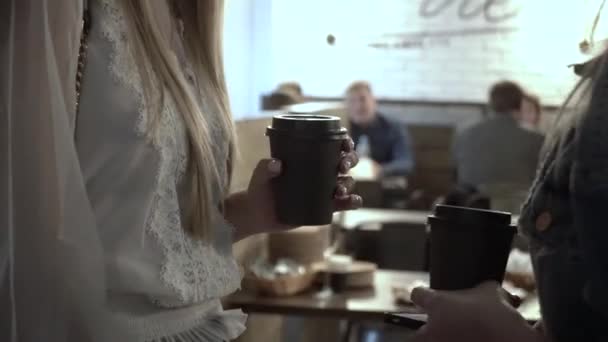 女孩们手牵着咖啡杯和智能手机站在咖啡店里 — 图库视频影像