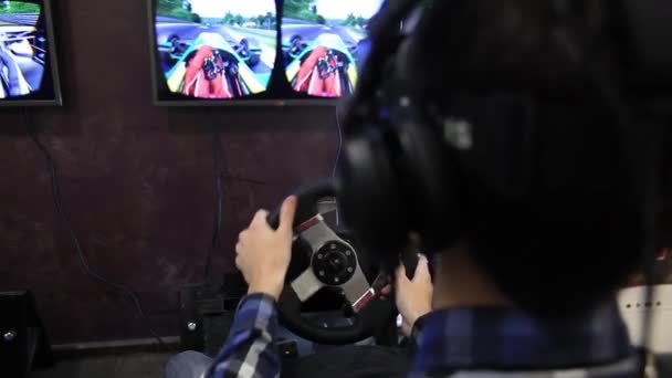 Ein junger Mann spielt ein Rennspiel und trägt eine Virtual-Reality-Brille — Stockvideo