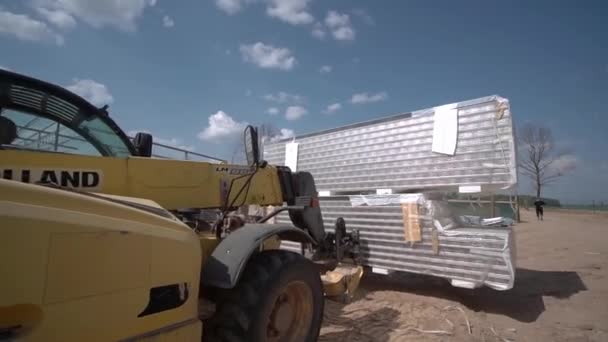 La cargadora transporta metal para la construcción del marco del taller de la futura planta. — Vídeo de stock