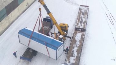 Bir vinç, bir müşteriye mal, kış konsepti, ithalat ve ihracat kavramları, üst görünüm, yükleme işleri göndermek için bir demiryolu platformuna yük taşır..