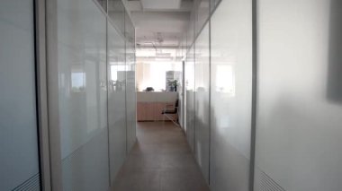 Kamera, ofis kompleksinin dar koridorundan, özel ofislerin kapısının önünden geçiyor..