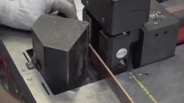 Um homem faz manualmente um canto de metal em uma máquina. — Vídeo de Stock
