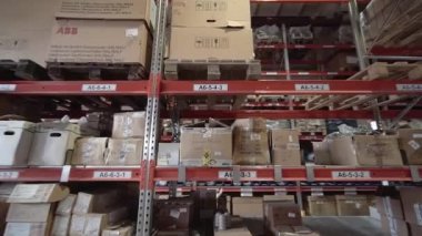 Büyük fabrika deposu. Kamera büyük bir mağazanın içindeki raflar arasında döner..