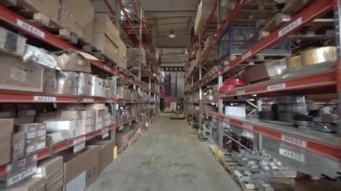 Büyük fabrika deposu. Kamera büyük bir mağazanın içindeki raflar arasında döner..