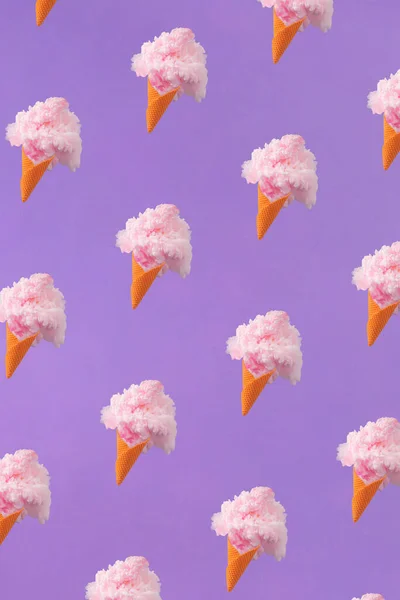 Summer trendy pattern made of orange ice cream cones with pastel pink color paint against purple background. Creative fun summer snack food idea. Abstract art.