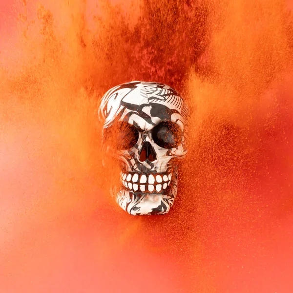 Skull with vibrant red powder explosion. Minimal horror Halloween background. Skull burning in fire abstract idea.