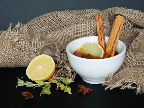 Limon, kuru otlar, anason, tarçın çubukları, bir fincan çay, mumlar ve çuval bezle sonbahar arkaplanı. Doğal siyah arkaplan. Şükran günün kutlu olsun..