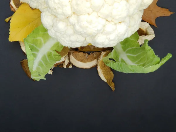 Sonbahar arkaplanı karnabahar, kurutulmuş porcini mantarı ve sonbahar yaprakları. Sonbahar mantarları, karnabahar ve siyah arka planda yaprakların bileşimi.