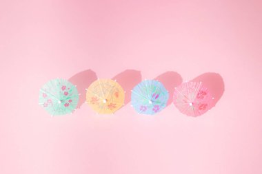 Pembe pastel arka planda rengarenk yaz plaj şemsiyesi. Minimum tasarım. Boşluğu kopyala.