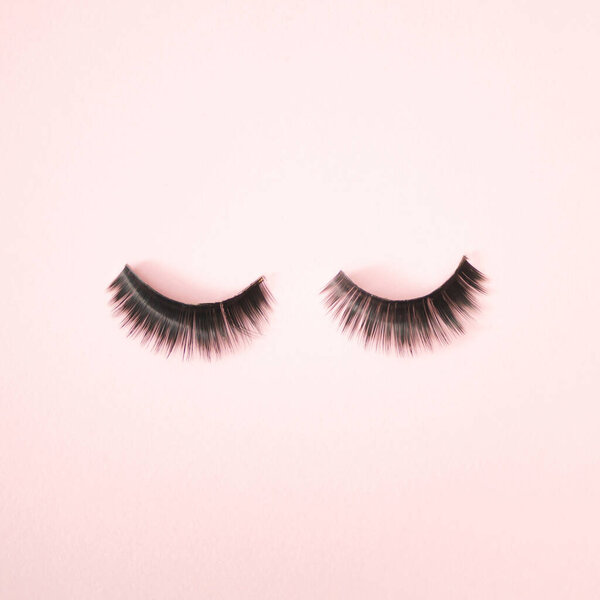 Two lashes on a pink background. Minimal make up design.