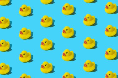 Mavi arka planda sarı plastik ördek. Desen.