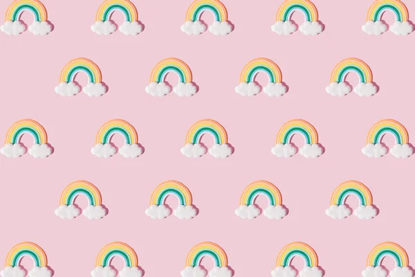 Small colorful rainbow cookie with clouds. Pattern. Pink background.