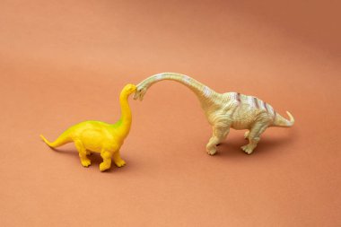 Kahverengi arka planda iki dinozor. Plastik oyuncaklar. En düşük tasarım.
