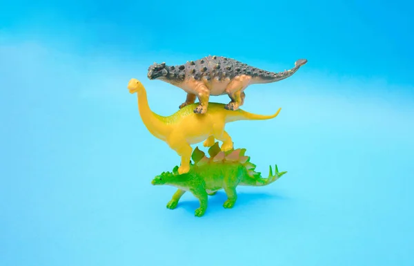 三只恐龙彼此站在蓝色的背景上 塑料玩具 — 图库照片