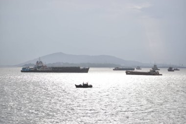 Mumbai, Hindistan 18 Kasım 2021. Arka planda dağlar olan deniz suyunda balıkçı teknesi. Denizde balık tutan balıkçı.