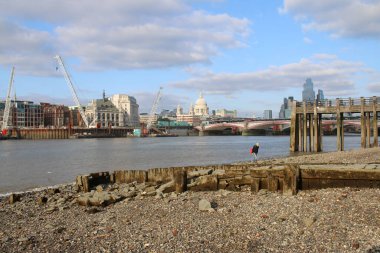 Londra, İngiltere - 3 Eylül 2021: Stony mud larkers 'dan peyzaj şehri manzarası Thames Nehri' nin güney kıyısında, Globe yakınlarındaki gökdelenleri ve Tate 'in St. Paul katedrali arka planı ve rıhtımdaki ahşap tekne limanlarına sahip. 