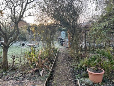 Bahçe Kış manzarası Norfolk İngiltere 'de dondurucu soğuk sabah manzarası espalier armut ağacı lavanta çalısı kışın verimsiz ağaçlar ve gül kemeri ve gri gökyüzü altında gizli bir kapı ve yol ile bitkiler