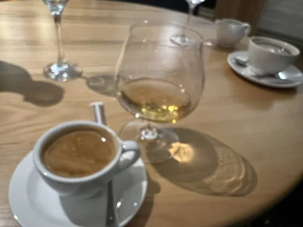 严冬假期 宾馆餐厅里 用白瓷杯和茶匙盛的特级咖啡和用泡沫和白兰地调的茶匙盛的黑色茶碟在餐桌前 从上而下 — 图库照片