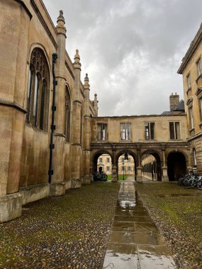 Cambridge, Doğu Anglia / İngiltere - 22 Şubat 2022: Peterhouse College Cambridge Üniversitesi gri gökyüzü ile yağmurlu bir günde kemer ve giriş koridorlu tarihi bina