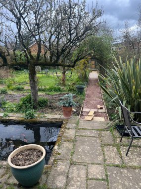 Tasarım projesinin bahçe manzarası, antika geri dönüşümlü ev tuğlalarıyla çitlere düz bir yol inşa etmek, havan ve kenar sınırları espalier armut ağacı, çimen çimen ve bitkilerle döşenmiş. 