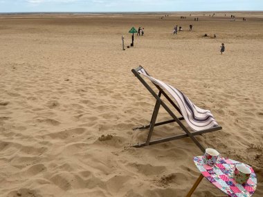 Kumlu kumsaldaki manzara, güzel kuyularda esen rüzgarlı esinti ilkbaharda Norfolk Doğu Anglia 'nın yanında ve açık mavi gökyüzüyle tatilde sahilde yürümenin keyfini çıkaran figürler. 