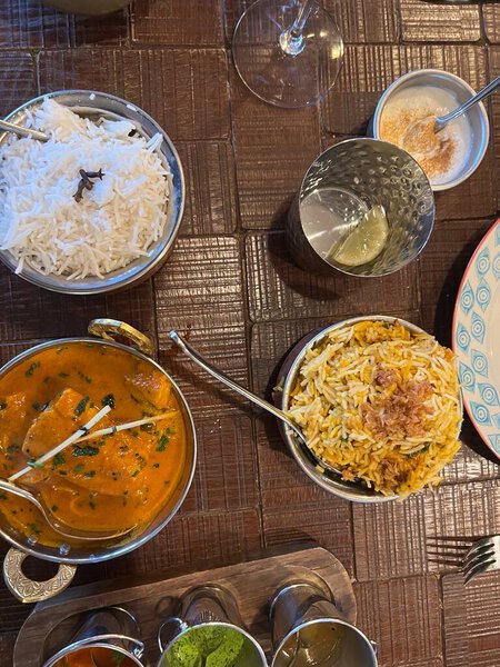 Close up of traditional Indian evening meal in restaurant with delicious rice dishes, sauces and tasty vegan main course cooked with hot spices coriander dressing and chilli and served on wood table 