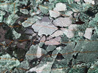 Close up of broken glass, the translucent sharp shattered pieces from a vw soft top heated car window pane all smashed and fallen into rear shelf of car interior 