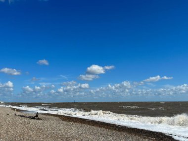Landscape view of beautiful Walberswick beach East Anglia Suffolk uk with sea waves pebble sand shore with natural grassy banks and blue sky with white cloud on Summer holiday day light