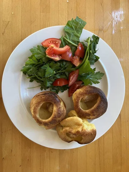 Close up of mini Yorkshire pudding with vegan sausages, these individual hand made Toad in the Hole snacks served with lettuce tomato salad on white plate flat lay view for breakfast lunch or dinner